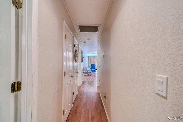 hall with baseboards, visible vents, wood finished floors, and a textured wall