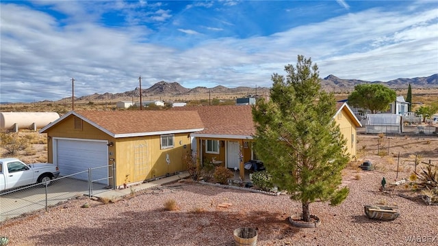 ranch-style home with driveway, a garage, fence, and a mountain view