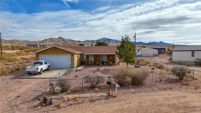 ranch-style house featuring a garage, fence, a mountain view, and concrete driveway