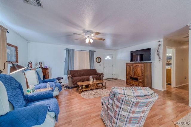 living area featuring light wood-type flooring, baseboards, visible vents, and a ceiling fan