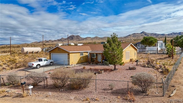 single story home with a mountain view, driveway, an attached garage, and fence