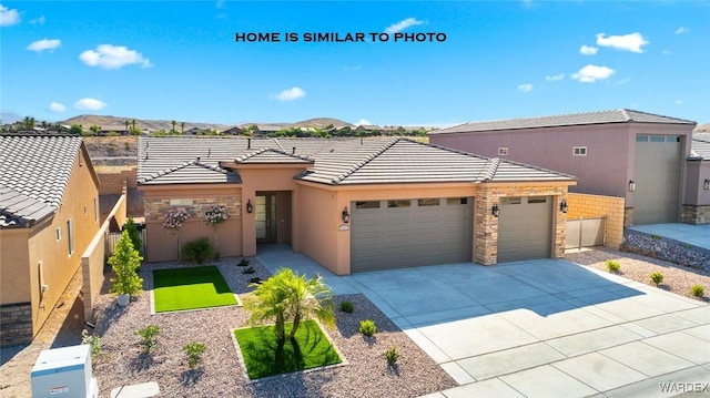 view of front of property with stucco siding, an attached garage, a mountain view, driveway, and a tiled roof