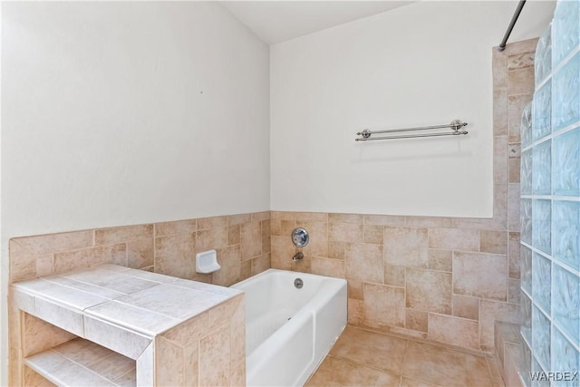 full bathroom featuring a garden tub, tile walls, wainscoting, a tile shower, and tile patterned floors