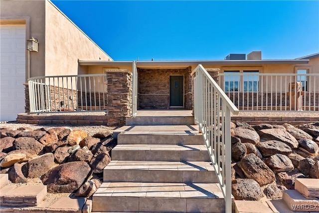 view of exterior entry with a garage, stone siding, and stucco siding