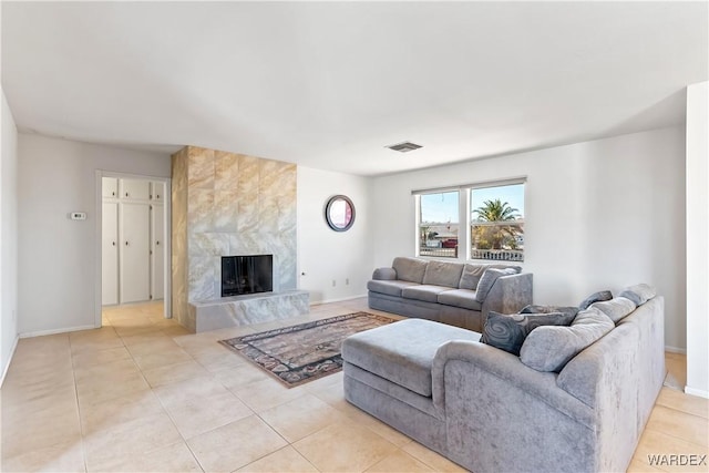 living room with light tile patterned floors, baseboards, a premium fireplace, and visible vents