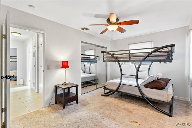 carpeted bedroom with visible vents, a ceiling fan, and tile patterned floors