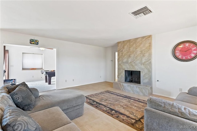 living room featuring tile patterned flooring, a fireplace, visible vents, and baseboards