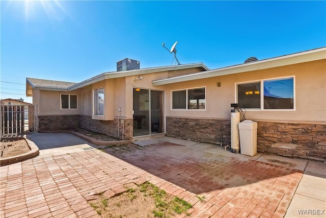 rear view of property with stone siding, a patio area, and stucco siding