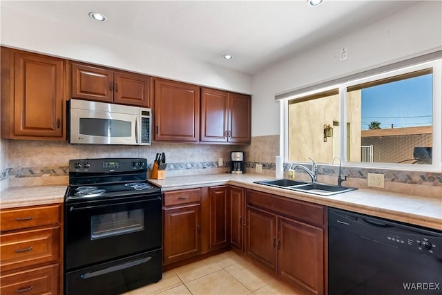 kitchen featuring black appliances, tile counters, backsplash, and a sink