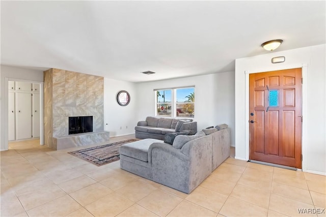 living area featuring light tile patterned flooring, baseboards, visible vents, and a tile fireplace