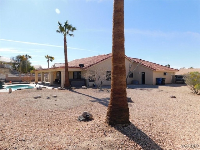 rear view of house with a fenced in pool, a tile roof, a patio area, and stucco siding