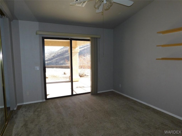 carpeted empty room with a ceiling fan, a mountain view, and baseboards