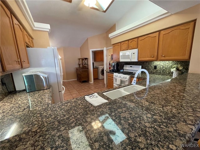 kitchen featuring brown cabinets, washer / clothes dryer, backsplash, white appliances, and a peninsula