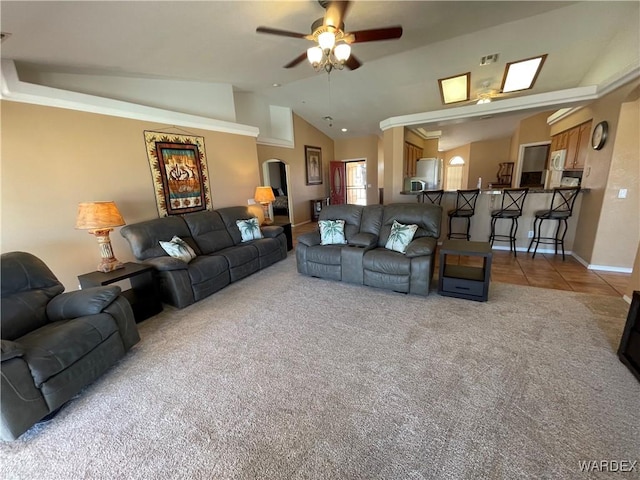 carpeted living room featuring lofted ceiling, ceiling fan, visible vents, baseboards, and tile patterned floors