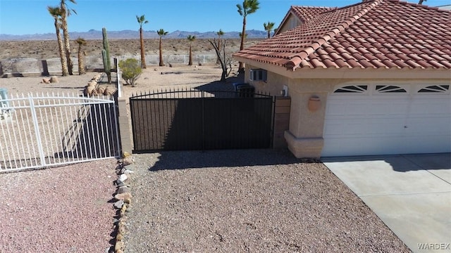 view of side of property with an attached garage, a tile roof, fence, driveway, and stucco siding