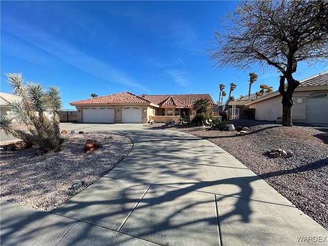 view of front of home featuring a garage, a tiled roof, concrete driveway, and stucco siding