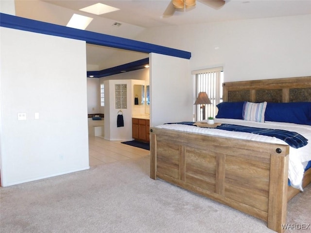 bedroom featuring light tile patterned floors, lofted ceiling, light colored carpet, a ceiling fan, and ensuite bath