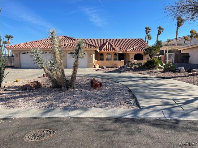 mediterranean / spanish home with a garage, concrete driveway, a tiled roof, and stucco siding