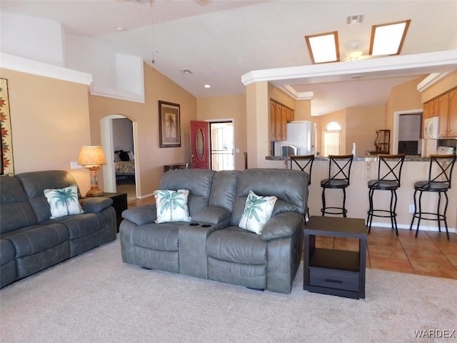 living room with arched walkways, light tile patterned flooring, light carpet, visible vents, and vaulted ceiling