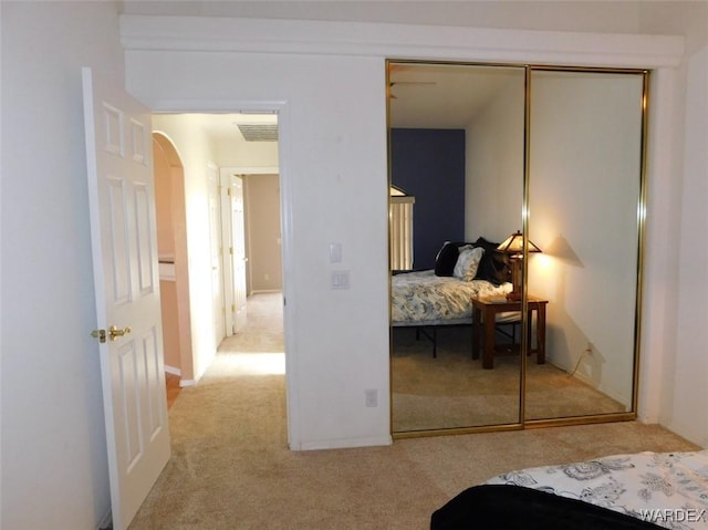 bedroom with arched walkways, a closet, light colored carpet, and visible vents