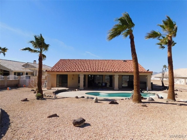 rear view of house with a fenced in pool, a tile roof, a patio, and stucco siding