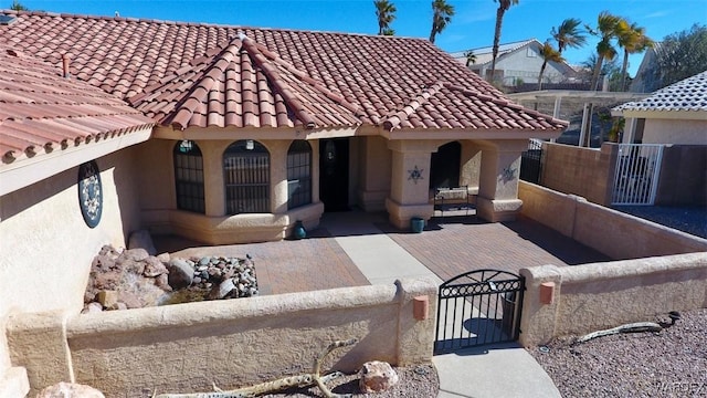 view of front of house with stucco siding, a fenced front yard, a gate, and a tile roof