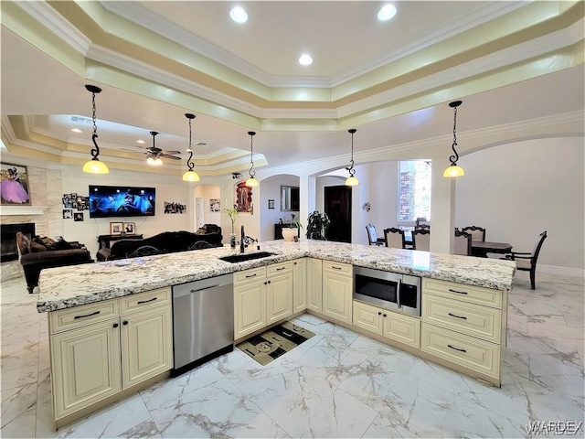 kitchen featuring arched walkways, stainless steel appliances, open floor plan, a tray ceiling, and decorative light fixtures