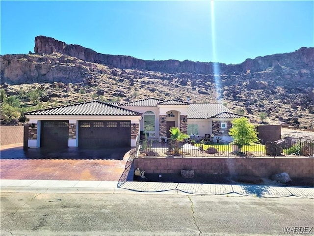 view of front of house with driveway, a fenced front yard, a tile roof, and a mountain view