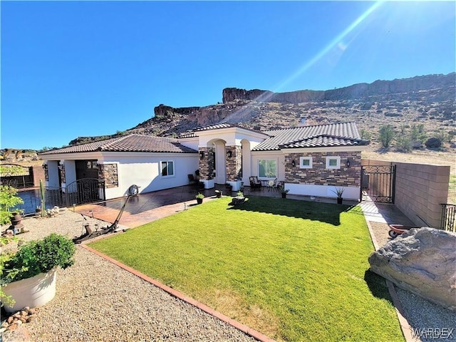 view of front of home featuring a tiled roof, a gate, fence, a mountain view, and stucco siding