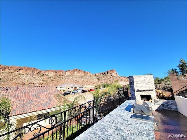 exterior space with an outdoor stone fireplace, a mountain view, and an outdoor kitchen