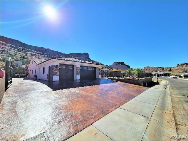 exterior space with a garage, a tile roof, a mountain view, and stucco siding