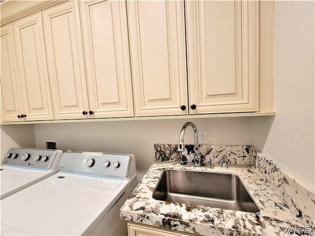 clothes washing area featuring cabinet space, a sink, and washer and clothes dryer