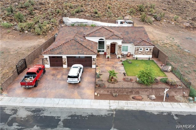 view of front of house with a fenced front yard, stucco siding, an attached garage, driveway, and a tiled roof