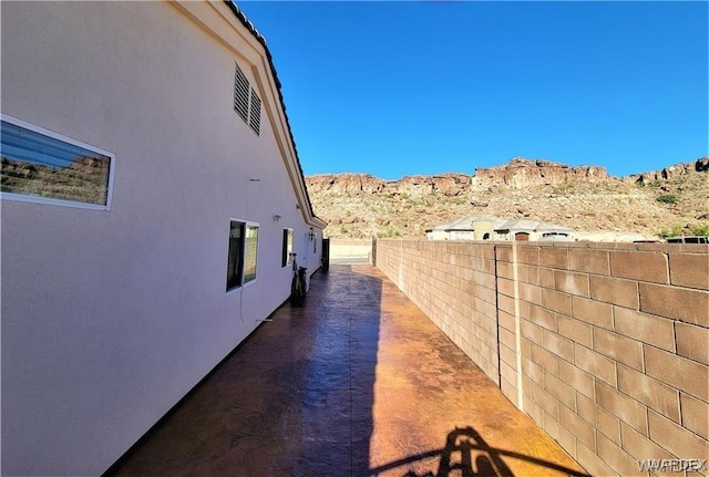view of property exterior with a mountain view, fence, and stucco siding
