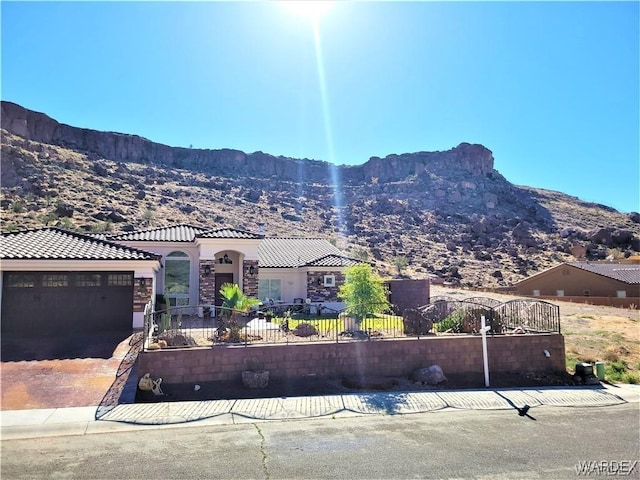 view of front of house featuring a fenced front yard, a mountain view, a garage, a tiled roof, and driveway