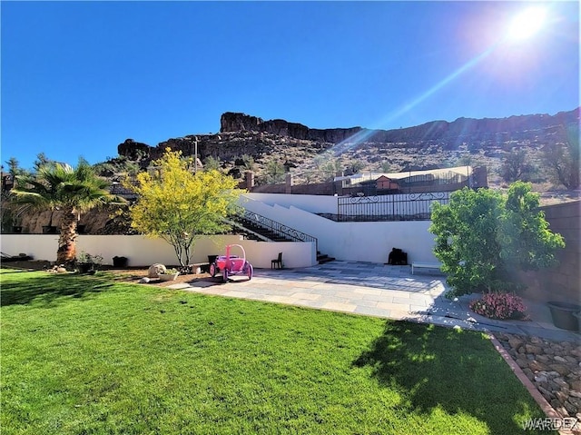 view of yard with stairs, a mountain view, fence, and a patio