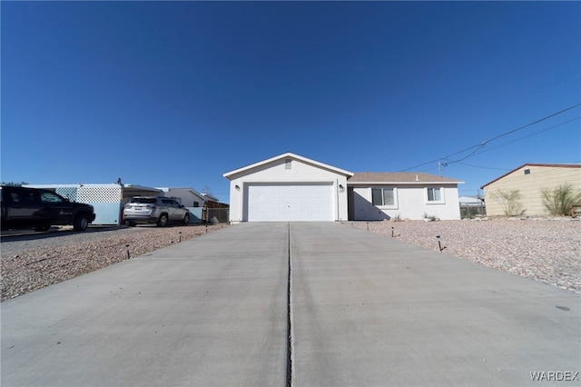 ranch-style home featuring a garage, concrete driveway, and fence