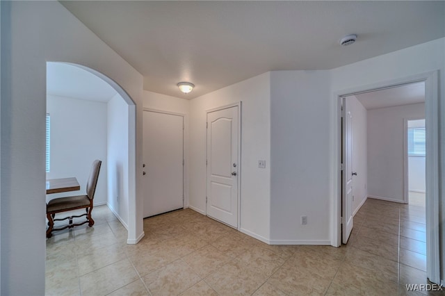 entrance foyer with light tile patterned floors, baseboards, and arched walkways