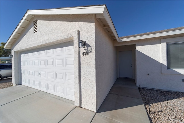 exterior space with concrete driveway, an attached garage, and stucco siding