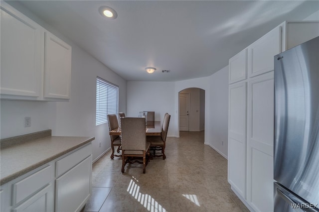 dining area with baseboards, visible vents, arched walkways, and light tile patterned flooring