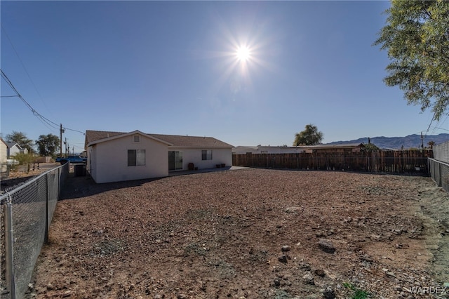 rear view of property featuring a fenced backyard, a mountain view, and stucco siding