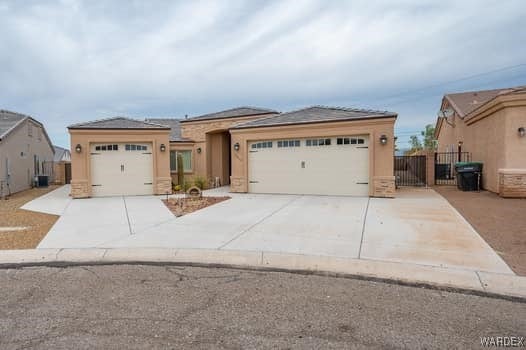 view of front of house featuring a garage, driveway, fence, and stucco siding