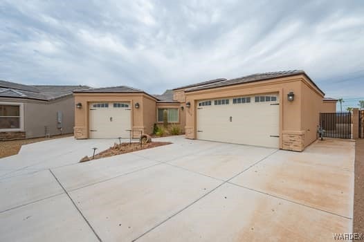 view of front facade featuring an attached garage, driveway, fence, and stucco siding