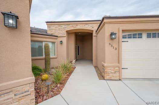 view of exterior entry with a garage, stone siding, and stucco siding