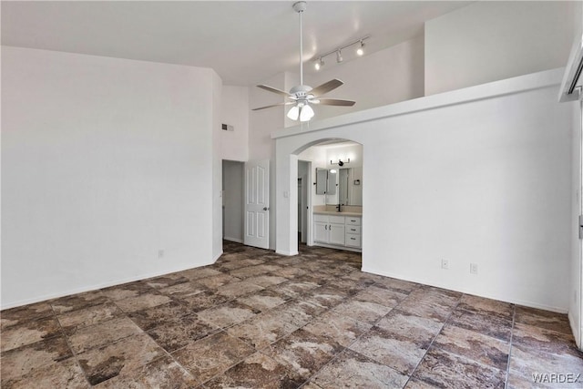 unfurnished bedroom featuring arched walkways, visible vents, connected bathroom, high vaulted ceiling, and baseboards