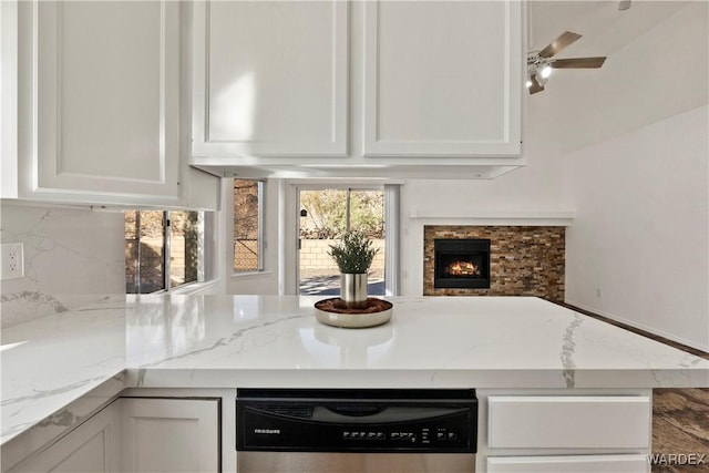 kitchen with tasteful backsplash, white cabinetry, dishwashing machine, and light stone countertops