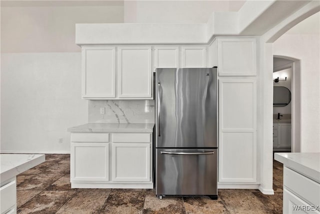 kitchen with freestanding refrigerator, white cabinets, and baseboards