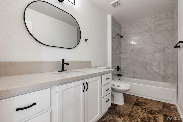 full bath with visible vents, toilet, stone finish flooring, vanity, and washtub / shower combination