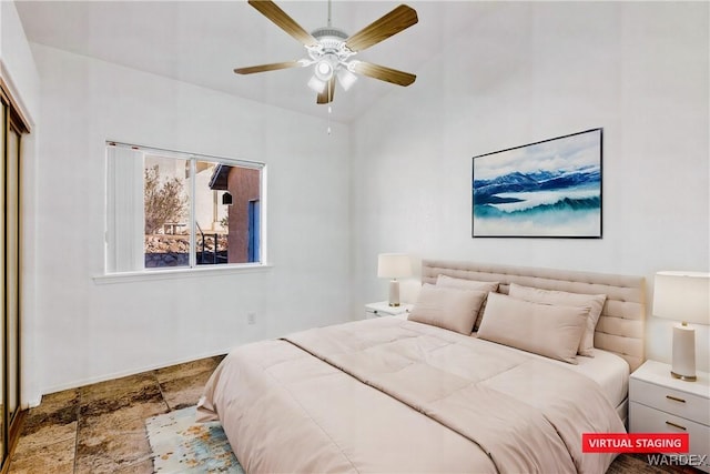 bedroom with baseboards, ceiling fan, stone finish floor, and a closet