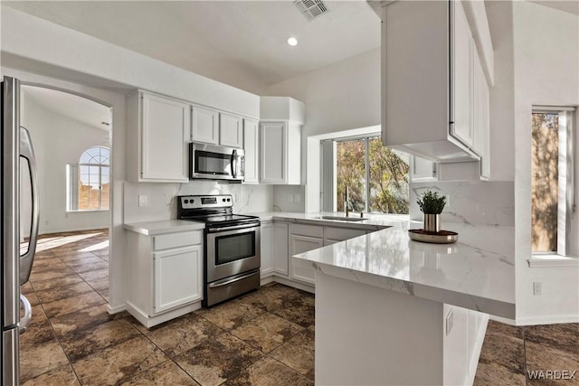 kitchen with light countertops, visible vents, appliances with stainless steel finishes, white cabinets, and a peninsula